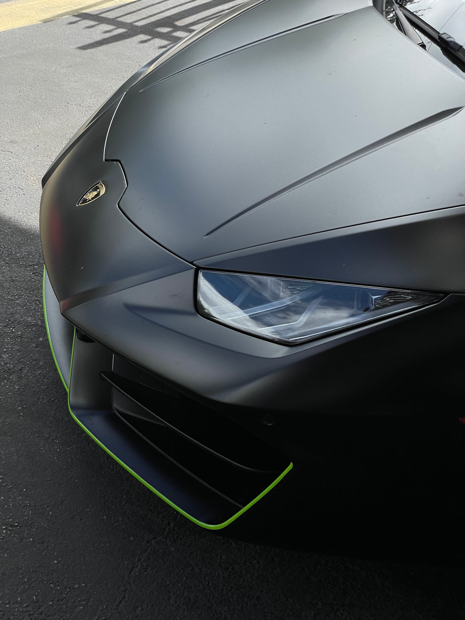 Detailaufnahme eines Lamborghini Huracán mit mattschwarzer Front und grünen Akzenten – aggressives Design eines Supercars, ideal für exklusive Sportwagenmiete und High-Performance-Erlebnisse über Drivable.