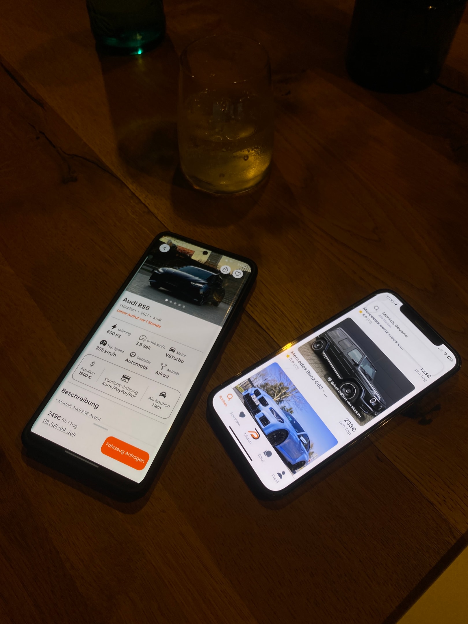 Drivable App auf zwei Smartphones auf einem Tisch mit Getränken – Anzeige von Sportwagen-Inseraten wie Audi RS6 und Mercedes G-Klasse, Sportwagen mieten und vergleichen direkt in der Drivable App.