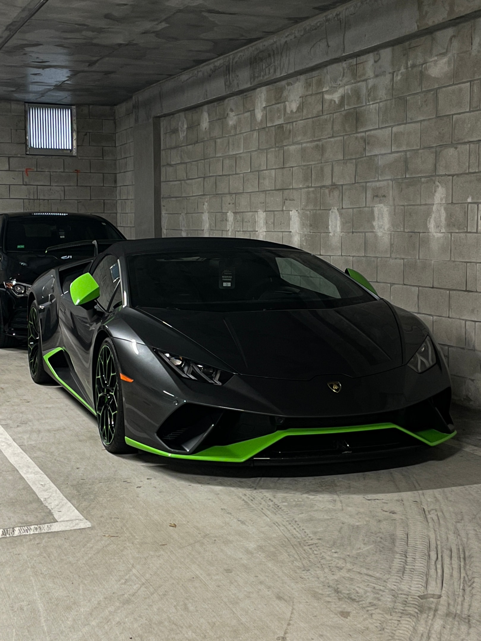 Lamborghini Huracán in Schwarz mit grünen Akzenten in einer Tiefgarage – aggressives Supersportwagen-Design für exklusive Sportwagenmiete und High-Performance-Erlebnisse über die Drivable App.