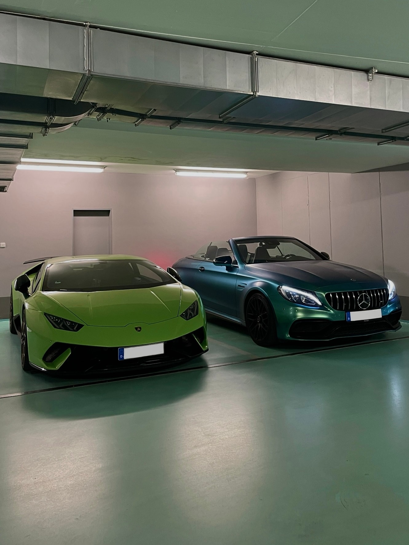 Lamborghini Huracán und Mercedes-AMG Cabrio in moderner Tiefgarage – exklusive Sport- und Luxuswagen für Premium-Sportwagenmiete über die Drivable App.