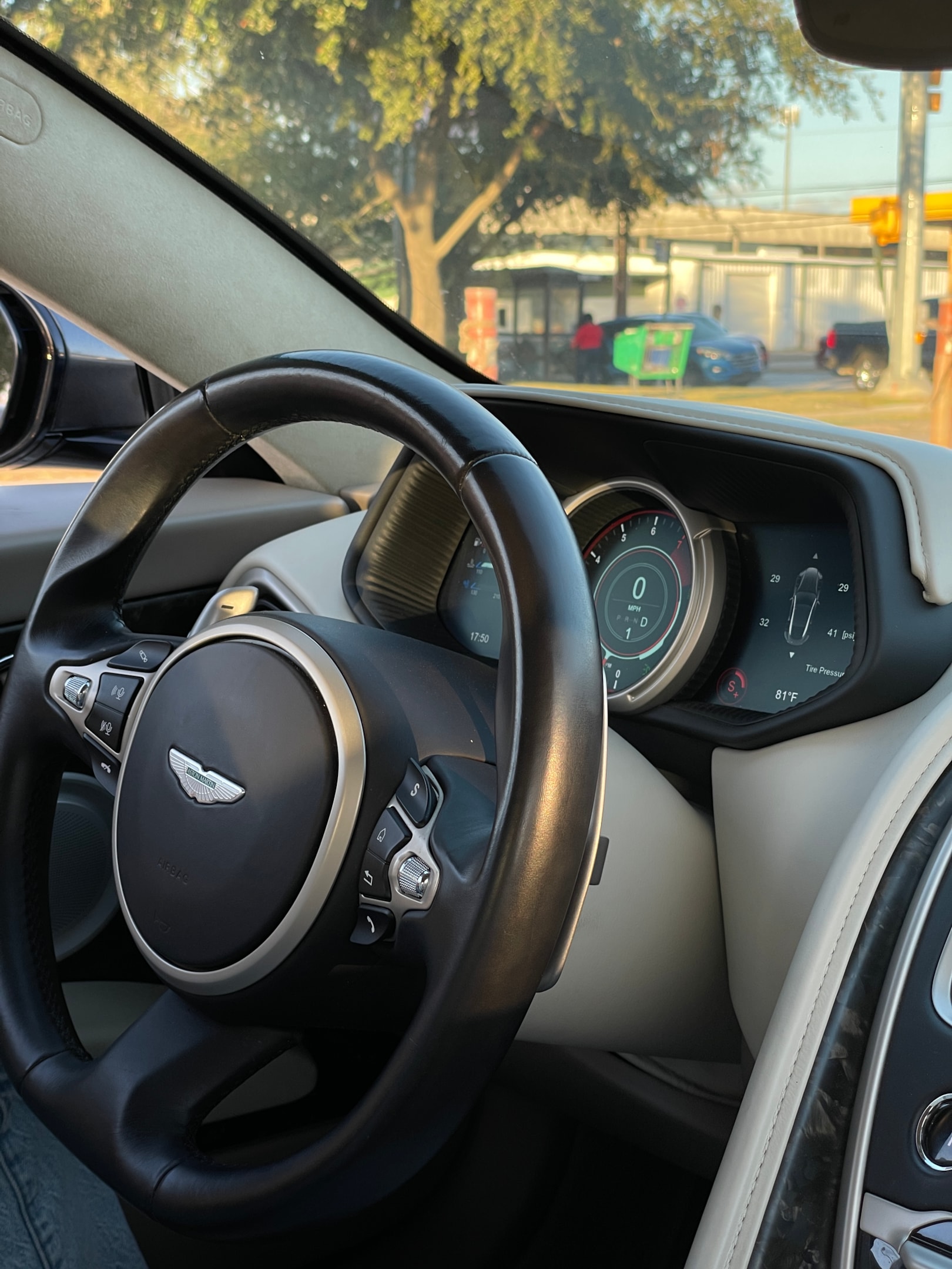 Luxuriöser Innenraum eines Aston Martin mit Lederlenkrad und digitalem Cockpit – Premium-Fahrerlebnis und exklusive Sportwagenmiete über die Drivable App.