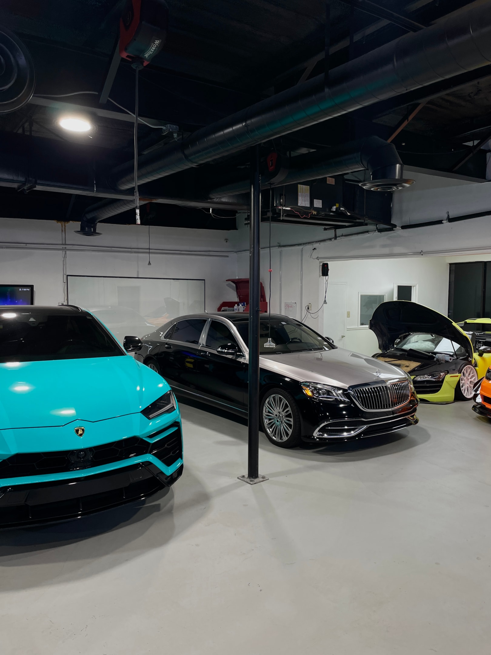 Luxus- und Sportwagen in moderner Fahrzeughalle mit Lamborghini Urus und Mercedes-Maybach – exklusiver Fuhrpark professioneller Vermieter für Premium- und Sportwagenmiete über die Drivable App.