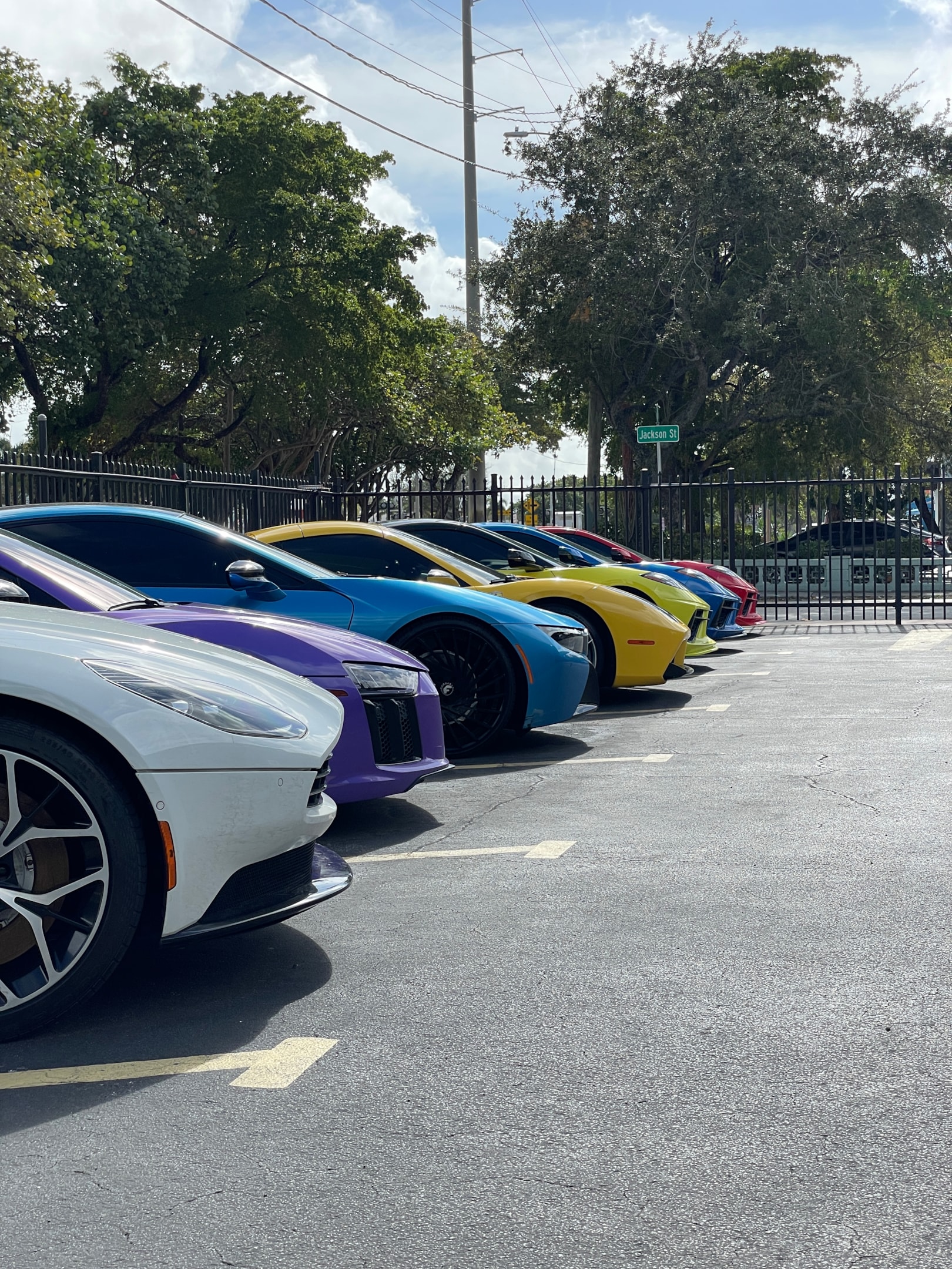 Reihe farbiger Luxus- und Sportwagen auf einem Parkplatz – exklusive Supersportcars in verschiedenen Farben, ideal für Sportwagen mieten und Premium-Erlebnisse über die Drivable App.